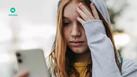 Une jeune fille pensive consulte son téléphone et pose sa main sur son front