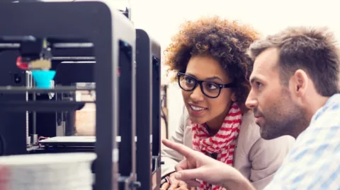 Un homme et une femme regardent une imprimante 3D