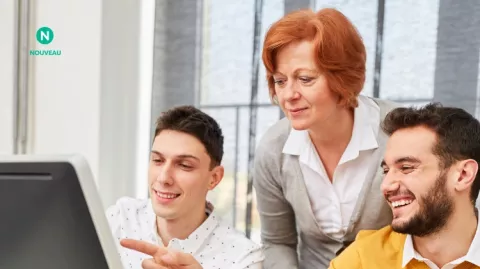 Deux jeunes hommes et une formatrice consultent un ordinateur lors d'une formation