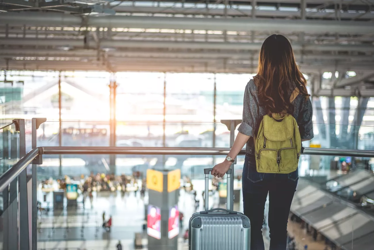 Une jeune femme se tient dans le hall d'un aéroport.