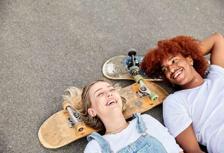 Des jeunes avec un skate sourient