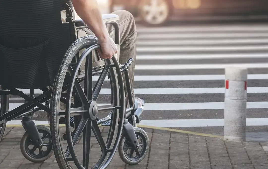 Personne en fauteuil roulant attendant de traverser la rue